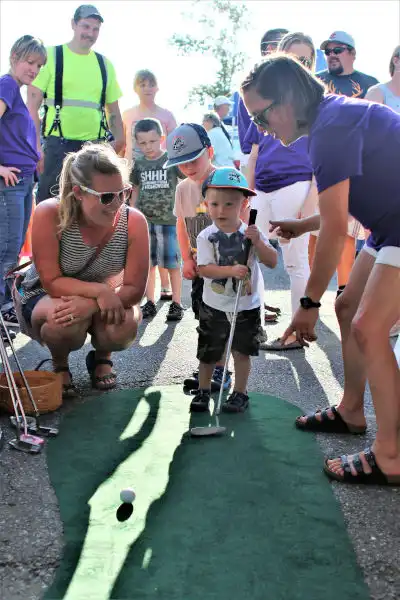 Team teaching child to golf for Port Susan Dental Care community service at National Night Out